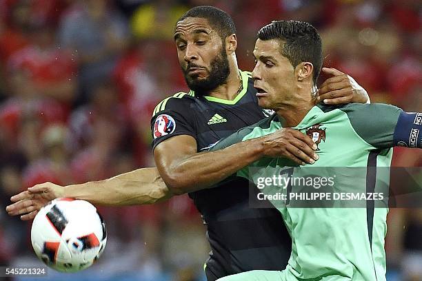Wales' defender Ashley Williams vies for the ball against Portugal's forward Cristiano Ronaldo during the Euro 2016 semi-final football match between...
