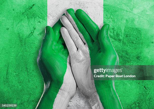 flag of nigeria painted on two hands together - nigeria flag stock pictures, royalty-free photos & images