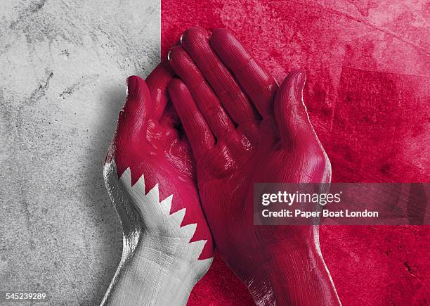 flag of qatar painted on two hands together - qatari flag stock pictures, royalty-free photos & images