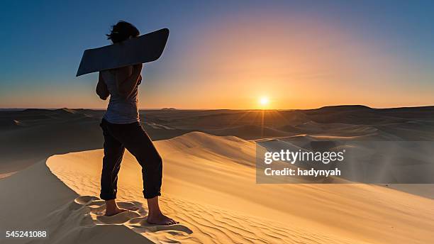 young woman sandboarding in the sahara desert during sunset, africa - sand boarding stock pictures, royalty-free photos & images