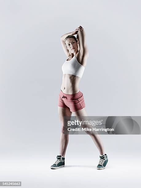 female exercising performing a tricep stretch - woman arms outstretched stock pictures, royalty-free photos & images
