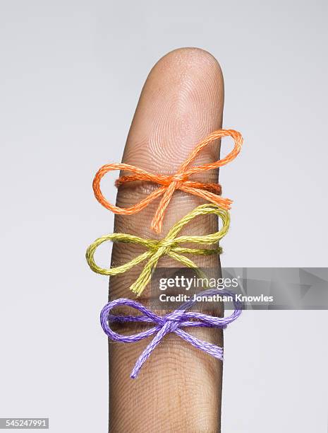 three string bows tied on a finger - fingertier stock pictures, royalty-free photos & images