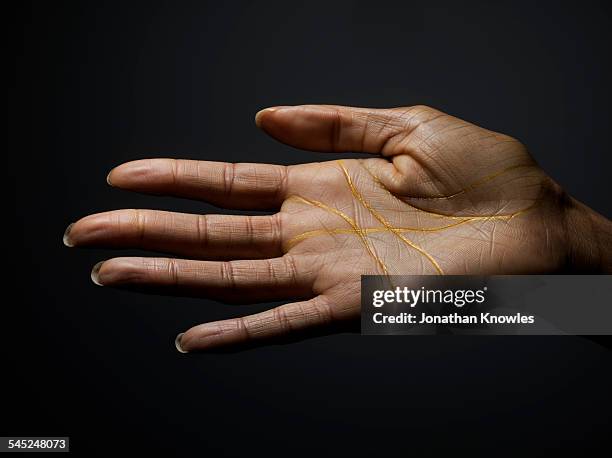 female dark skinned hand covered with gold lines - mano abierta fotografías e imágenes de stock