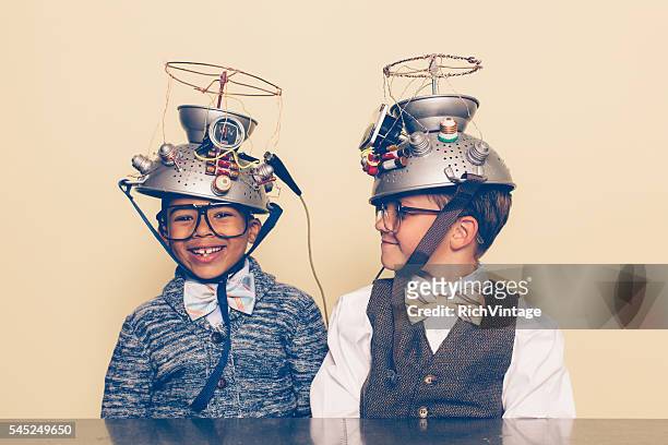 two boys dressed as nerds smiling with mind reading helmets - uitvinder stockfoto's en -beelden