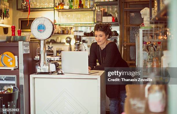 owner of coffee shop using a laptop - small business owners computer stock-fotos und bilder