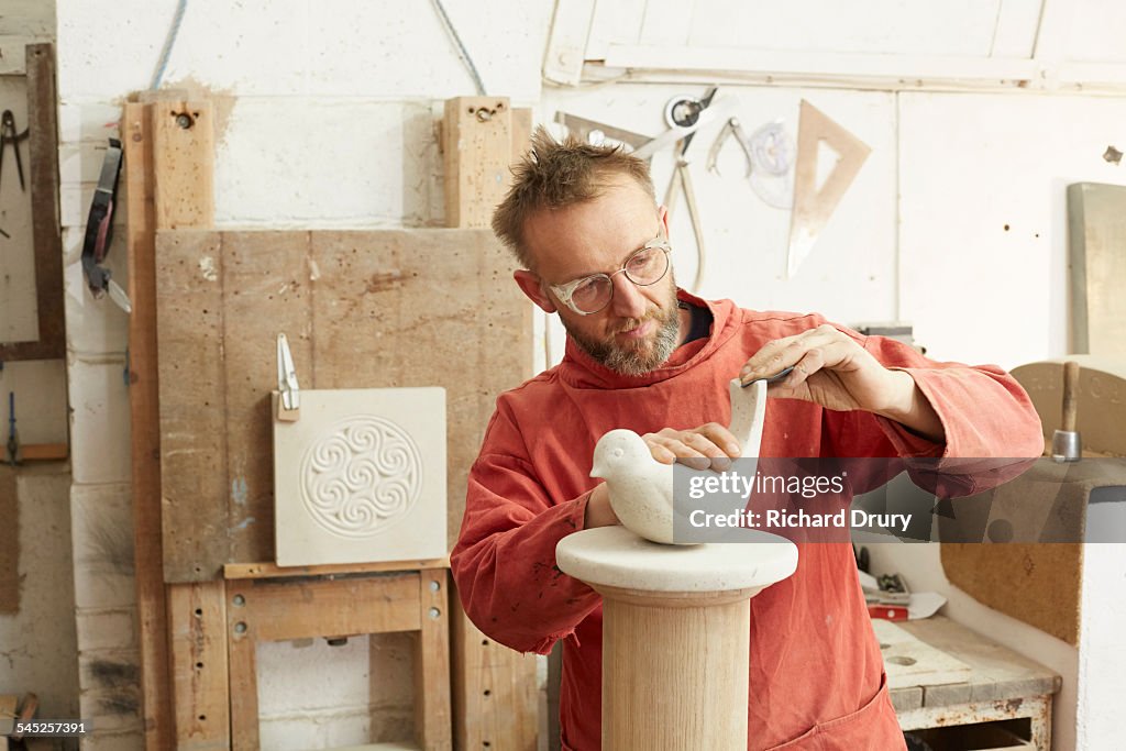 Stone carver sanding sculpture