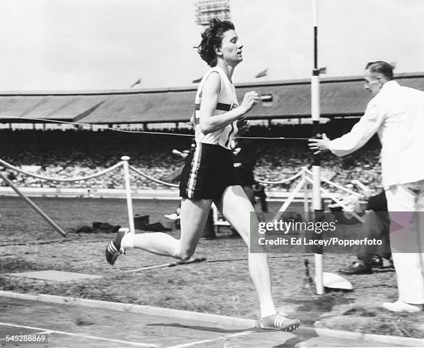 British middle distance runner Diane Leather crosses the finish line during a race at White City stadium in London, August 1st 1955.