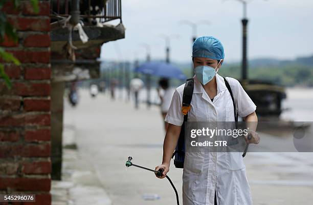 This picture taken on July 6, 2016 shows an epidemic prevention worker spraying disinfectant after flooding in Rongan in southern China's Guangxi...