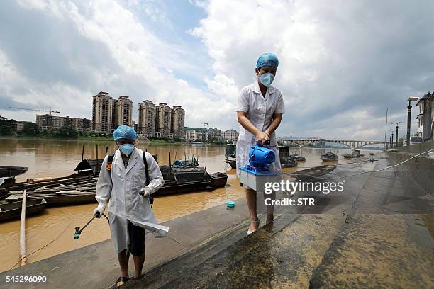 This picture taken on July 6, 2016 shows epidemic prevention workers spraying disinfectant after flooding in Rongan in southern China's Guangxi...