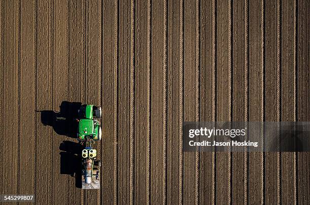 aerial view of tractor driving over bare dirt - tractor foto e immagini stock