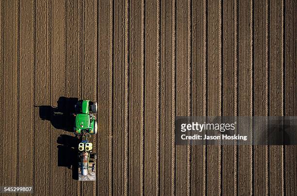 aerial view of tractor driving over bare dirt - tractor in field stockfoto's en -beelden