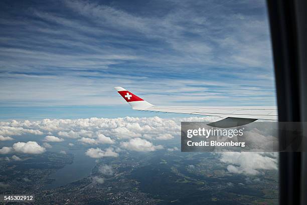 Swiss national flag sits on the wingtip of a Bombardier Inc. CS 100 C Series jet, operated by Swiss International Air Lines AG, as Lake Zurich sits...