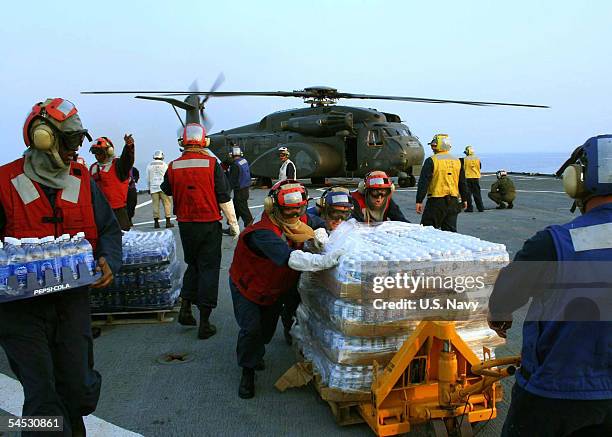 In this handout image provided by the U.S. Navy, U.S. Navy flight deck personnel take part in an emergency replenishment working party aboard the...