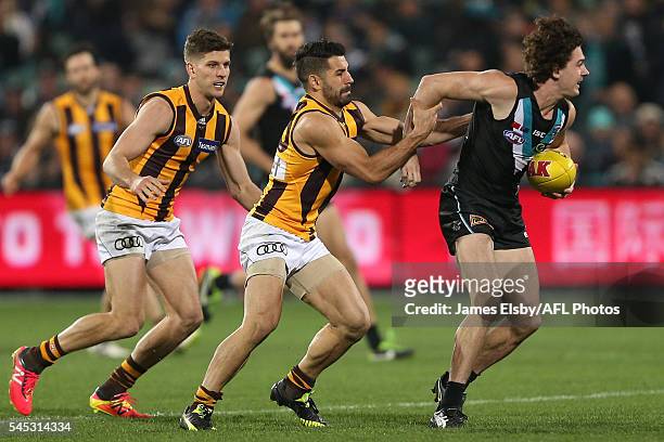 Darcy Byrne-Jones of the Power is tackled by Paul Puopolo of the Hawks during the 2016 AFL Round 16 match between Port Adelaide Power and the...