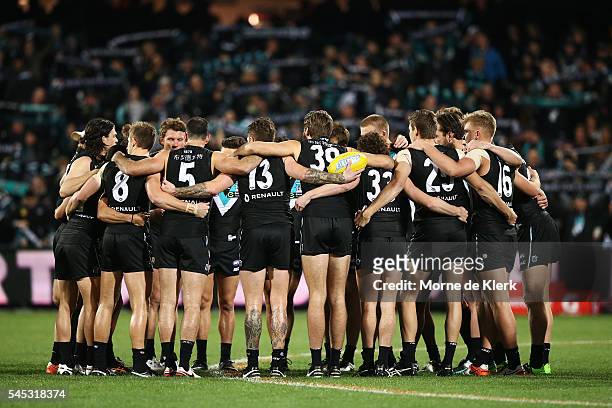 Spectators cheer on the Power as the team forms a huddle before the round 16 AFL match between the Port Adelaide Power and the Hawthorn Hawks at...