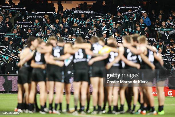 Spectators cheer on the Power as the team forms a huddle before the round 16 AFL match between the Port Adelaide Power and the Hawthorn Hawks at...