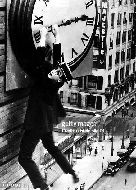 Film scenes Harold Lloyd 1893 - 1971 Actor, USA hanging on the hand from a large clock in the silent movie 'Safety Last'; director: Fred Newmeyer,...
