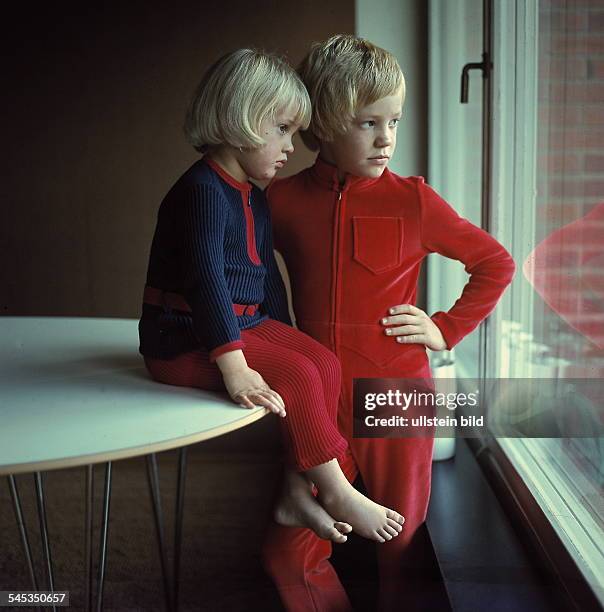 Zwei Kinder in Schlaf- undHausanzügen: roter Einteiler bzw. BlauesOberteil und rote Hose - 1971