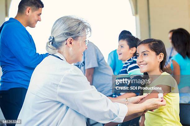 young girl getting a bandaid after receiving her flu shot - tetanus stock pictures, royalty-free photos & images