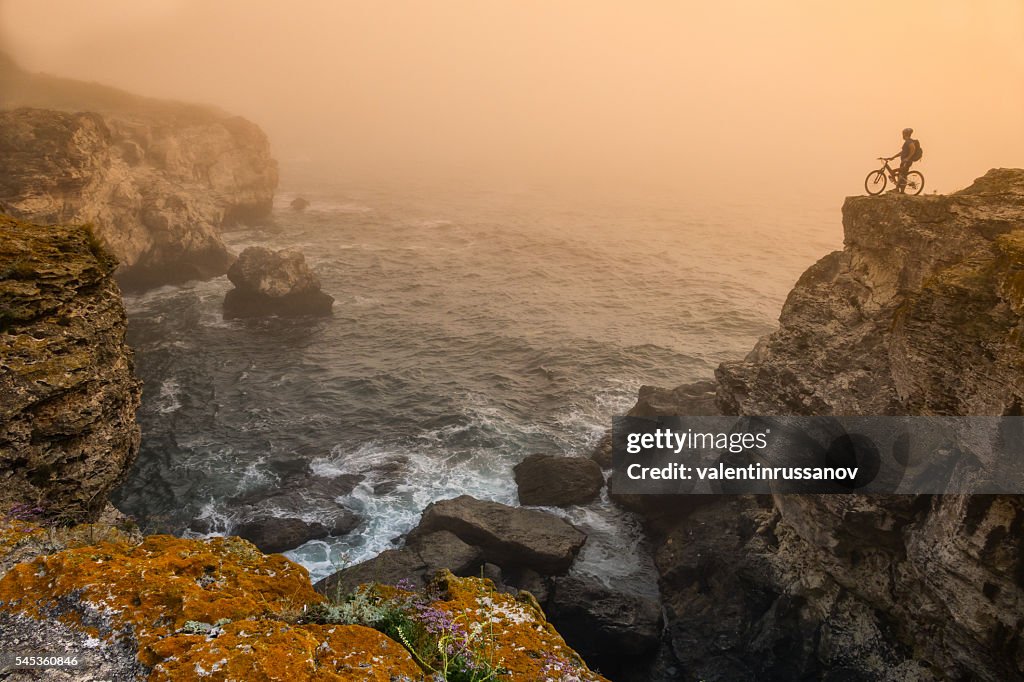 Mountainbiker standing on top of the cliff