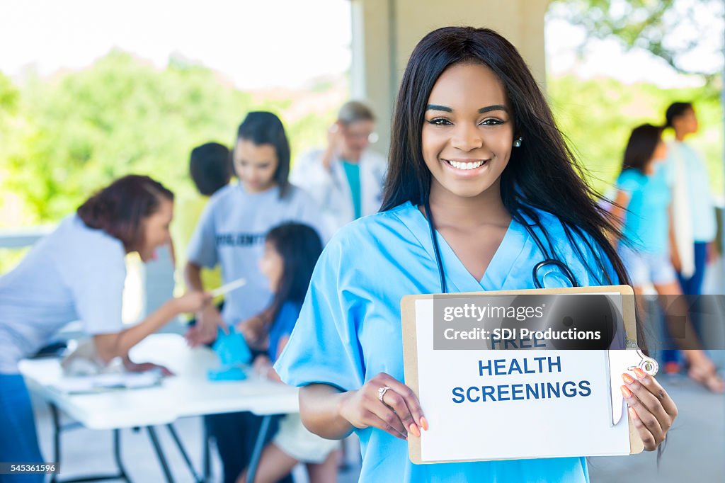 Hermosa mujer afroamericana sosteniendo un letrero de "Exámenes de salud gratuitos"