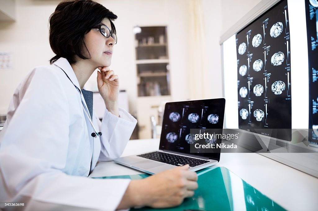 Concentrated female doctor examining MRIs in hospital