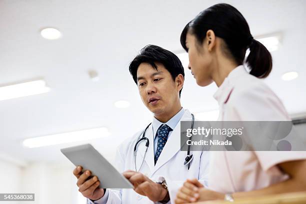 low angle view of doctor showing digital tablet in hospital - medical procedure stock pictures, royalty-free photos & images