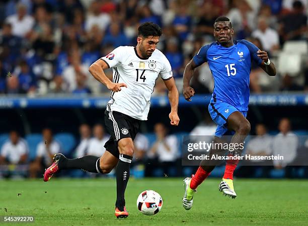 Emre Can of Germany runs with the ball under pressure from Paul Pogba of France during the UEFA EURO semi final match between Germany and France at...
