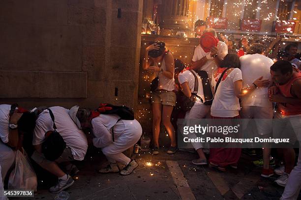 People take cover from flying sparks as the Toro del Fuego is run through the streets of Pamplona during the second day of the San Fermin Running of...