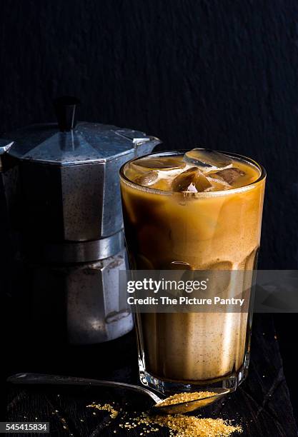 iced coffee with milk in a tall glass, moka pot, black background - moka pot stockfoto's en -beelden