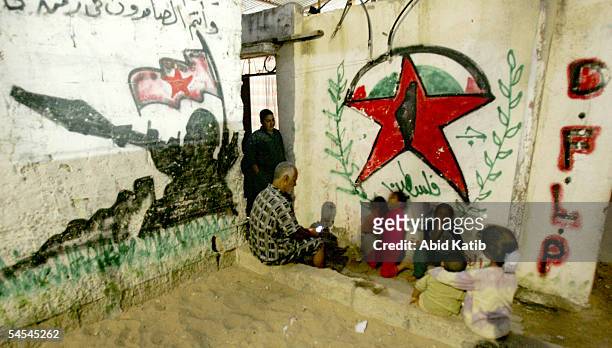 Palestinian family is seen as they sit next to the intifada graffiti in front their family home near the Jewish settlement of Neve Dekalim, September...