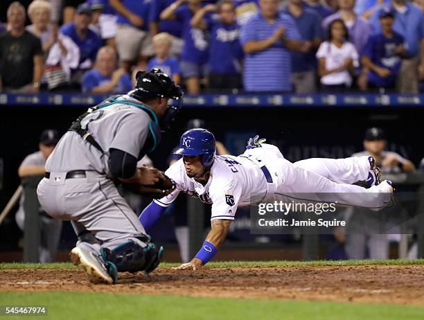 Cheslor Cuthbert of the Kansas City Royals slides safely into home plate to score as catcher Chris Iannetta of the Seattle Mariners misses the tag...