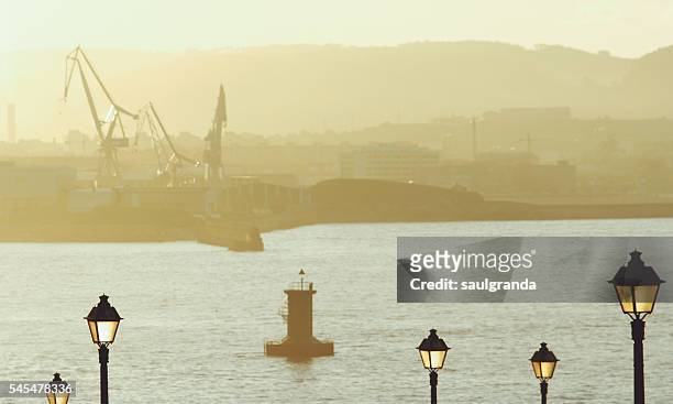 shipyard in dijon with a lighthouse and street lights in the foreground - gijon ストックフォトと画像