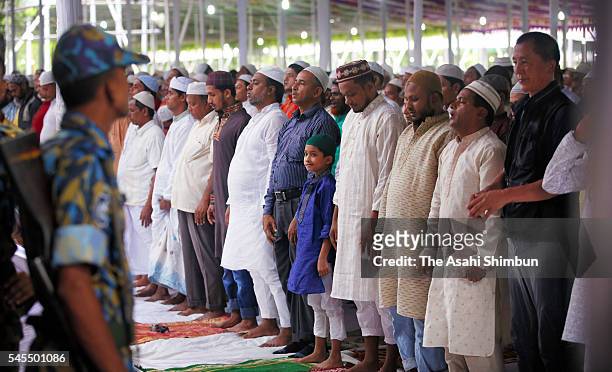 Muslims offer prayer to celebrate Eid ul-Fitr while armed police stand guard on July 7, 2016 in Dhaka, Bangladesh.