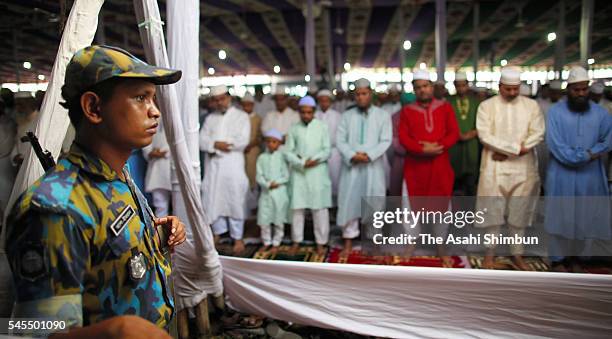 Muslims offer prayer to celebrate Eid ul-Fitr while armed police stand guard on July 7, 2016 in Dhaka, Bangladesh.