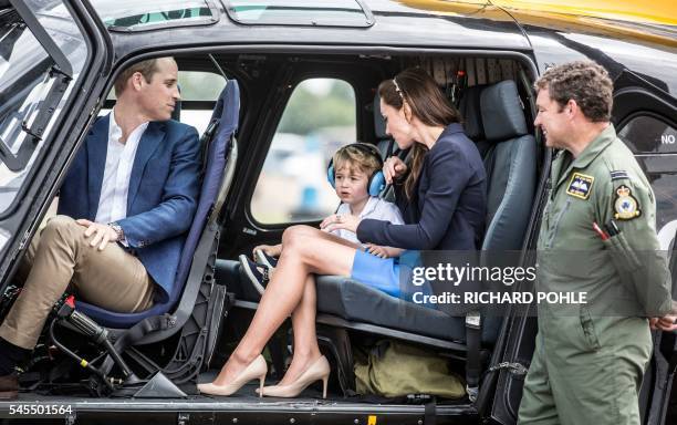 Britain's Prince George sits in a 'Squirrel' helicopter with his mother Catherine, Duchess of Cambridge and father Prince William during a visit to...