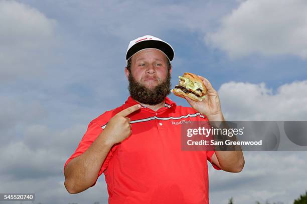 Andrew Johnston of England poses for a portrait with a hamburger after the third round of the World Golf Championships - Bridgestone Invitational at...