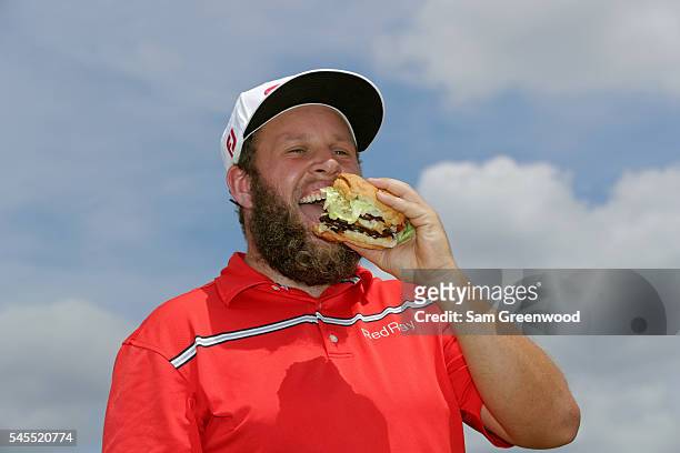 Andrew Johnston of England poses for a portrait with a hamburger after the third round of the World Golf Championships - Bridgestone Invitational at...