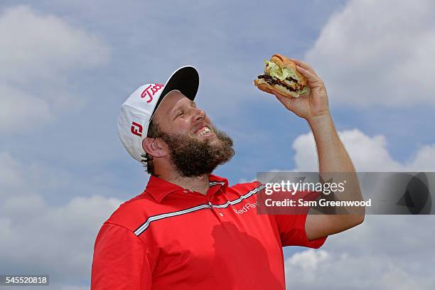 Andrew Johnston of England poses for a portrait with a hamburger after the third round of the World Golf Championships - Bridgestone Invitational at...