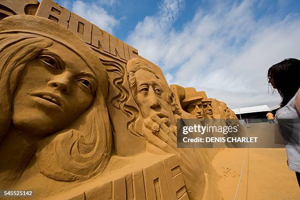 Woman looks at sand sculptures of French singers Serge Gainsbourg and Brigitte Bardot on the Touquet Beach, northern France, on July 8, 2016. Around...