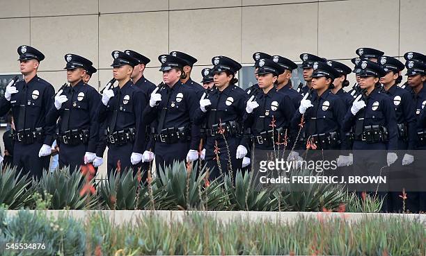 With black ribbons across their badge and holding a gun, police recruits attend their graduation ceremony at LAPD Headquarters where rappers Snoop...