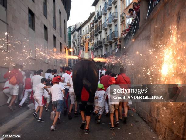 Man incarnating a "Toro de Fuego" chases people during the San Fermin Festival on July 8 in Pamplona, northern Spain. - Pamplona is host to the most...