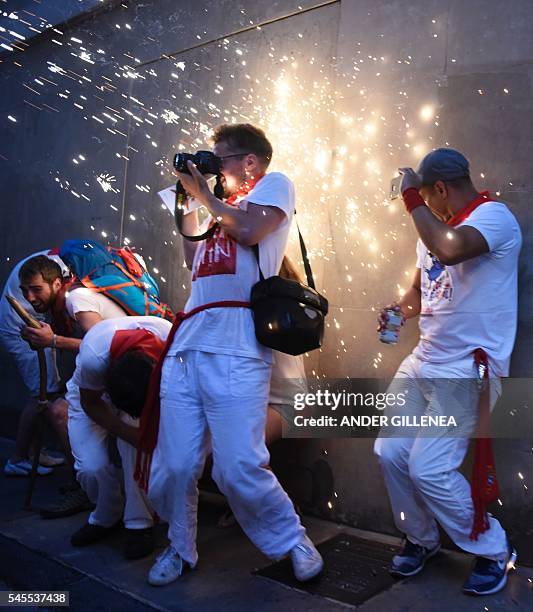 People protect themselves from the sparks falling from a "Toro de Fuego" during the San Fermin Festival on July 8 in Pamplona, northern Spain....