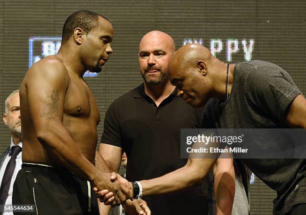 President Dana White looks on as mixed martial artist Anderson Silva shakes hands with and bows to mixed martial artist Daniel Cormier as they face...