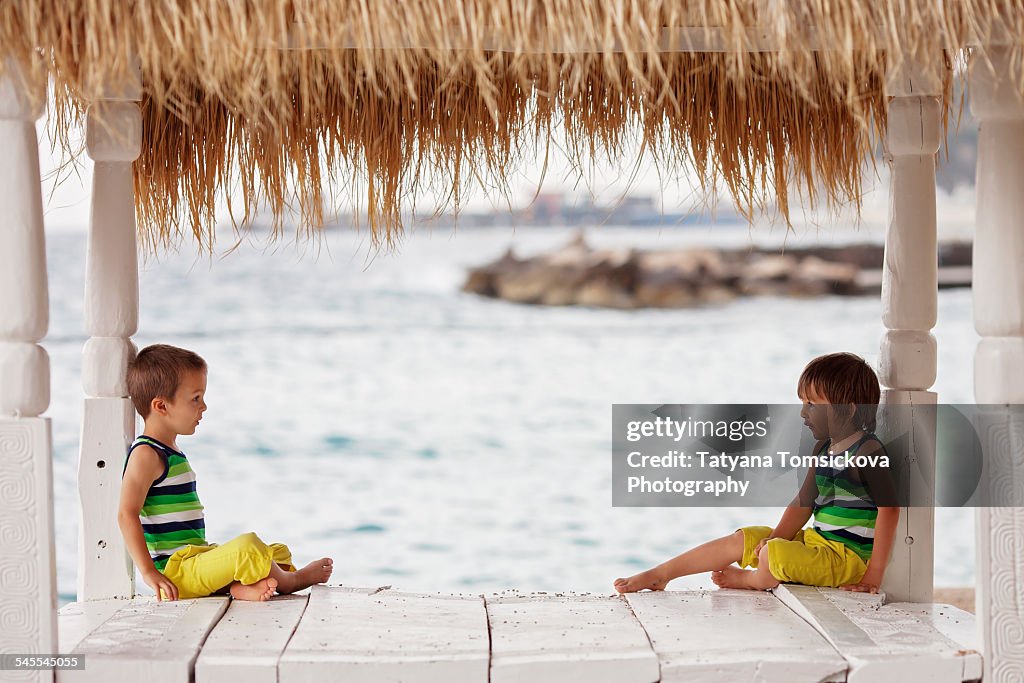 Two adorable boys, sitting on a beach bed