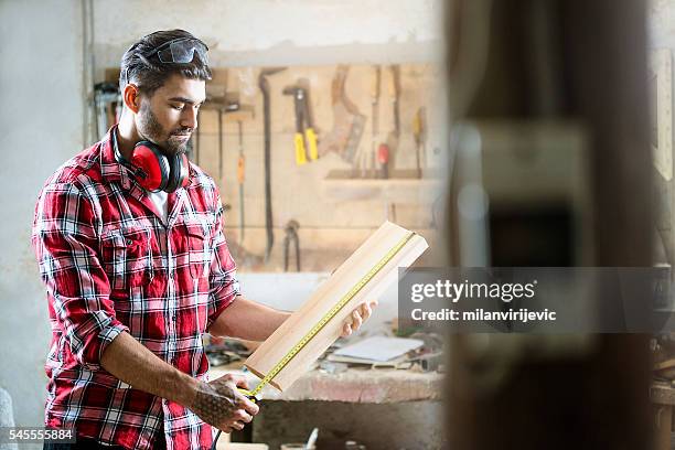 male carpenter measuring the board - independent stock pictures, royalty-free photos & images