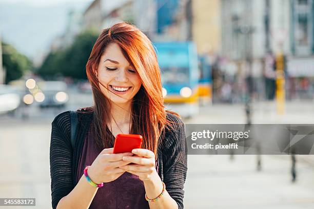 glückliche stadt mädchen sms - rote haare stock-fotos und bilder