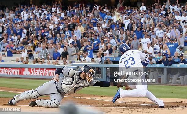 Adrian Gonzalez of the Los Angeles Dodgers avoids the tag of catcher Derek Norris of the San Diego Padres to score a run in the first inning at...