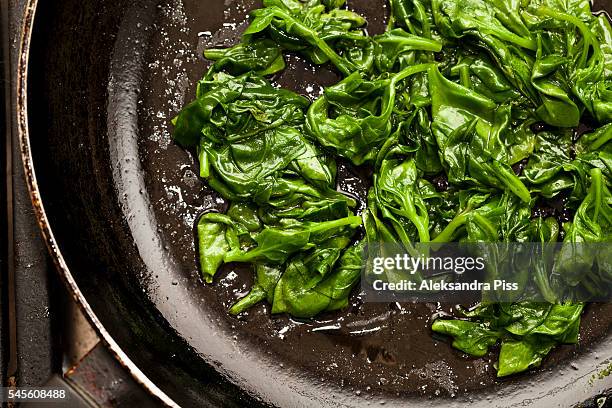 fresh sauted spinach on a pan - spinazie stockfoto's en -beelden