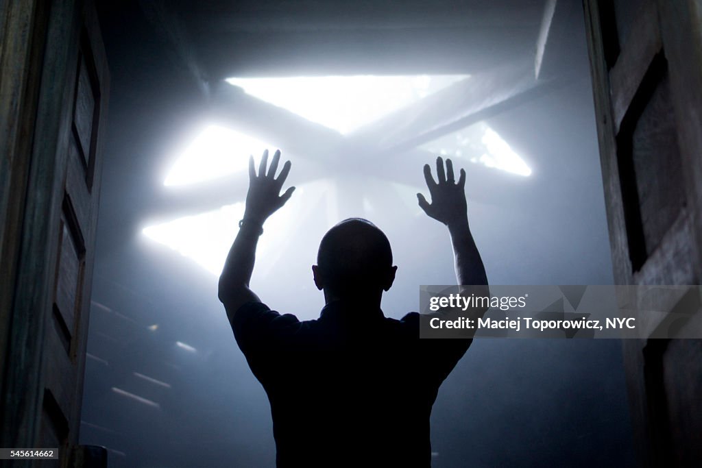 Silhouette of a man with raised hands against light coming from above.